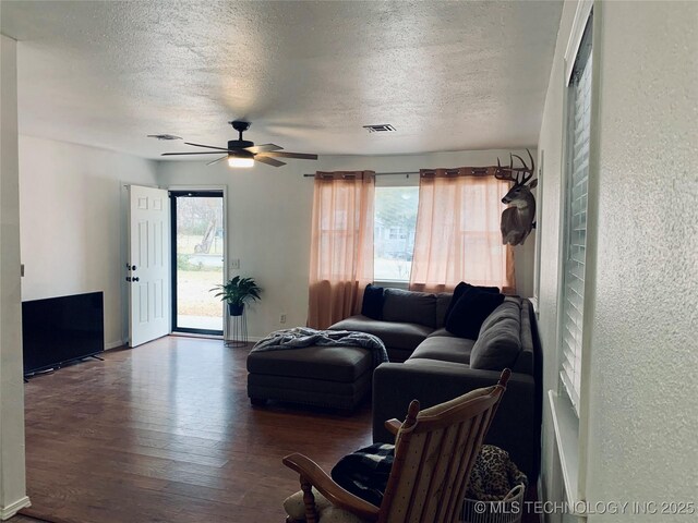 living room featuring visible vents, a textured ceiling, wood finished floors, and a textured wall