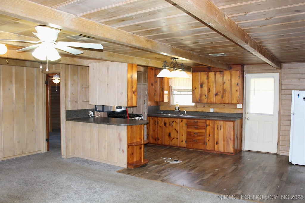 kitchen featuring dark countertops, wooden walls, beam ceiling, wooden ceiling, and freestanding refrigerator