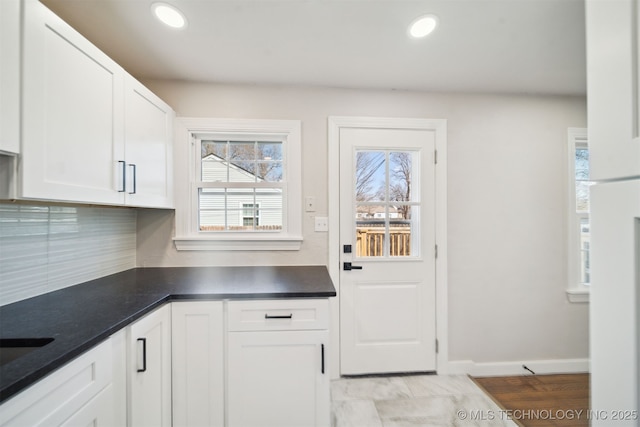 kitchen featuring dark countertops, tasteful backsplash, baseboards, recessed lighting, and white cabinetry