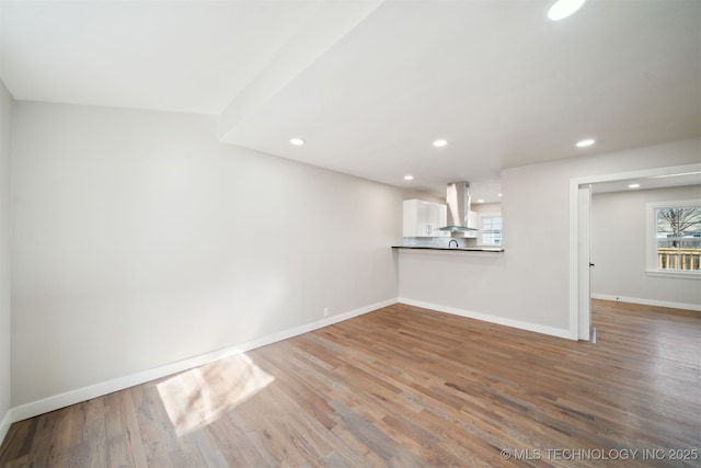 unfurnished living room with recessed lighting, baseboards, plenty of natural light, and wood finished floors