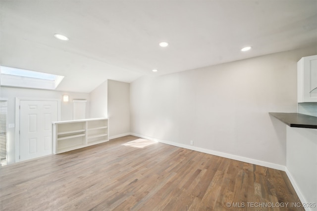 unfurnished living room with recessed lighting, light wood-type flooring, and baseboards