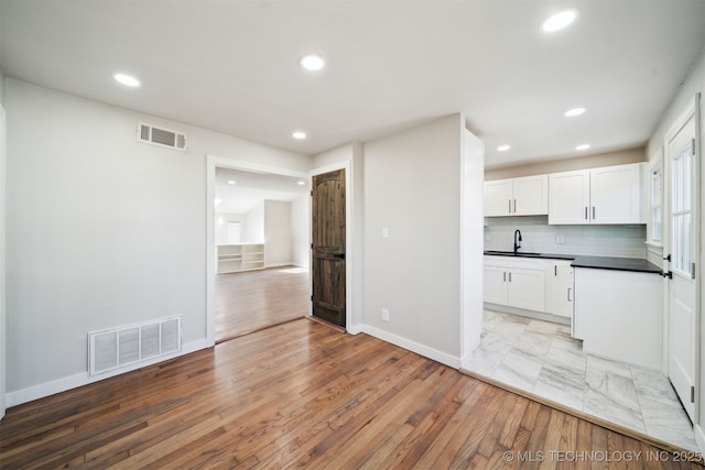 kitchen with a sink, visible vents, dark countertops, and white cabinets