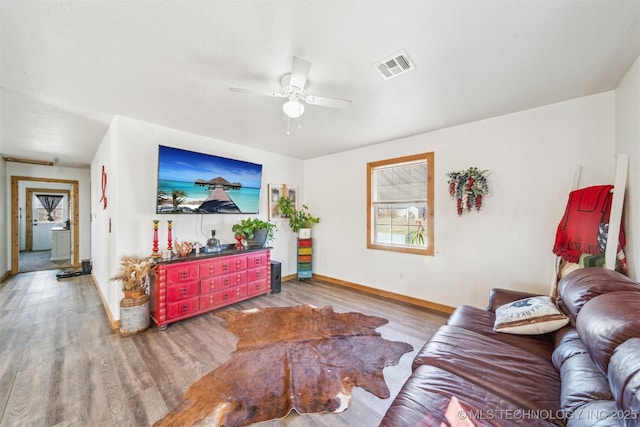 living area featuring visible vents, baseboards, ceiling fan, and wood finished floors