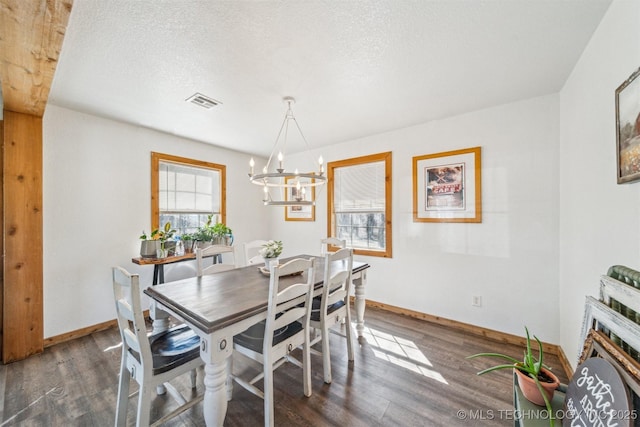 dining area featuring a chandelier, a textured ceiling, baseboards, and wood finished floors