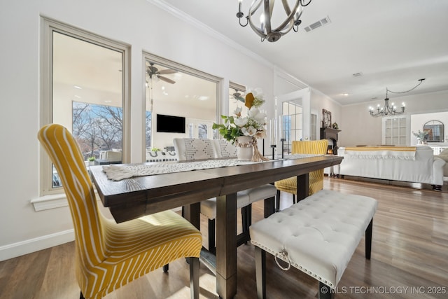 dining area with crown molding, wood finished floors, visible vents, and baseboards