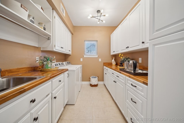 washroom with light tile patterned floors, baseboards, an inviting chandelier, cabinet space, and washer and dryer