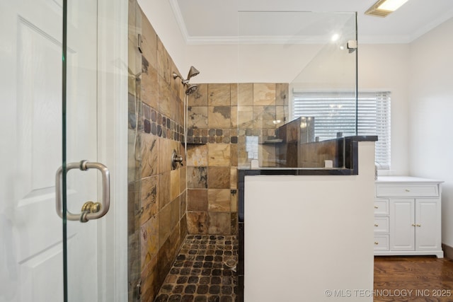 full bath with tiled shower, crown molding, and wood finished floors