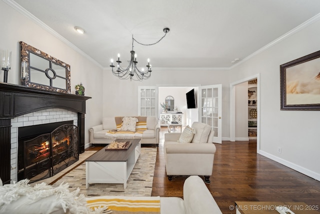 living area featuring a brick fireplace, baseboards, a chandelier, ornamental molding, and wood finished floors