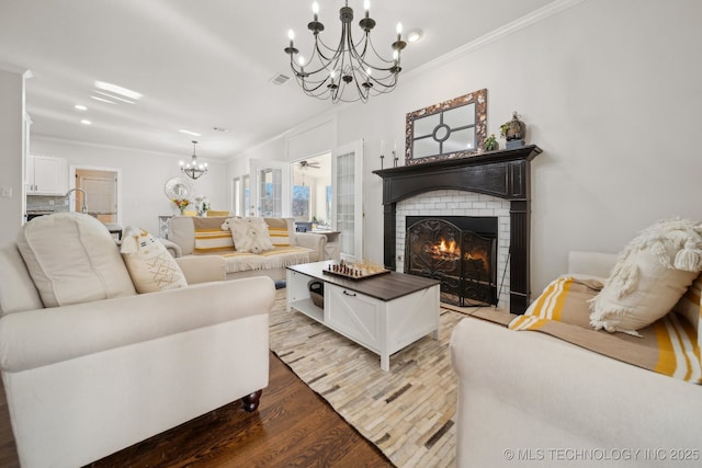 living area with visible vents, an inviting chandelier, wood finished floors, and crown molding