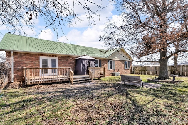 rear view of property with brick siding, french doors, a wooden deck, and fence