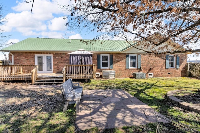 back of house featuring brick siding, cooling unit, metal roof, french doors, and a deck