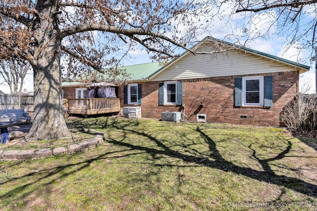 back of property with a lawn, central AC, fence, a wooden deck, and brick siding