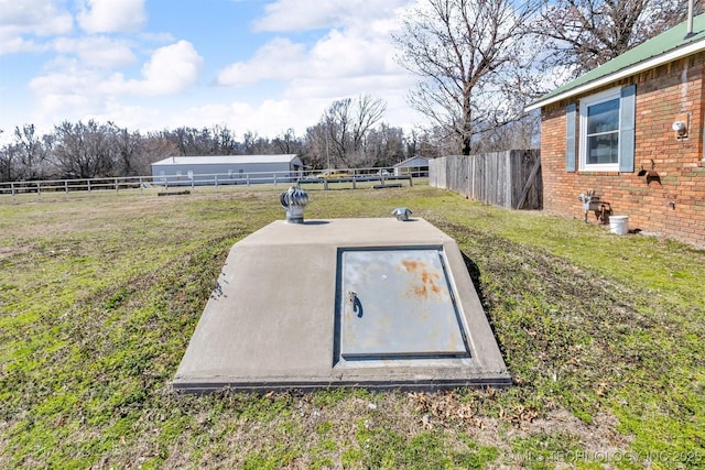 entry to storm shelter featuring a yard and fence