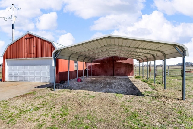 view of car parking with a carport, a detached garage, and fence