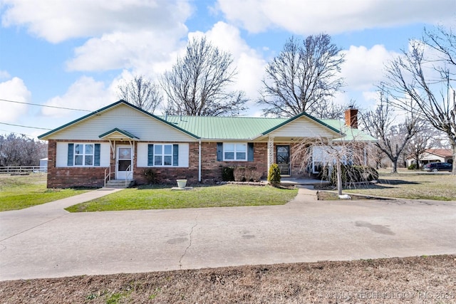 view of front facade featuring fence, a front yard, metal roof, brick siding, and a chimney