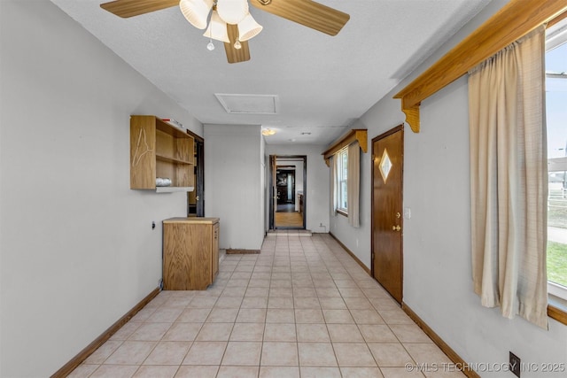 hallway with light tile patterned floors, baseboards, plenty of natural light, and attic access