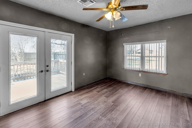 unfurnished room featuring visible vents, french doors, a textured ceiling, and wood finished floors