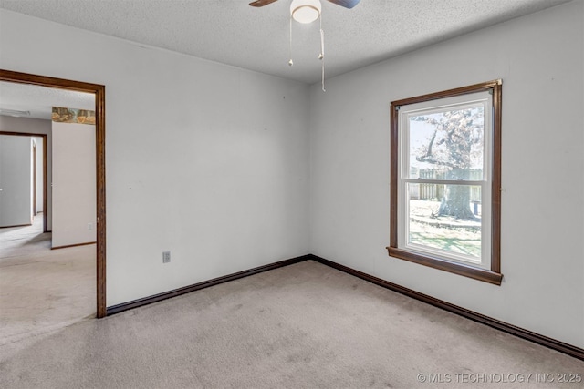 empty room featuring ceiling fan, light colored carpet, baseboards, and a textured ceiling