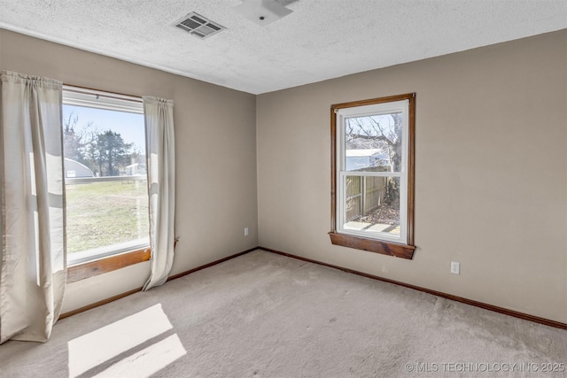 unfurnished room with visible vents, carpet floors, a textured ceiling, and baseboards