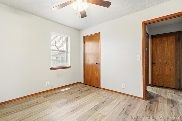 unfurnished bedroom with wood finished floors, baseboards, a closet, and a textured ceiling