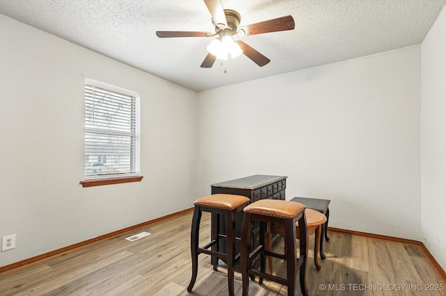 dining area featuring a textured ceiling, baseboards, visible vents, and light wood-type flooring