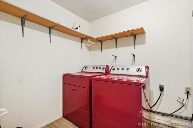 washroom with light wood-style floors, separate washer and dryer, laundry area, and a textured ceiling