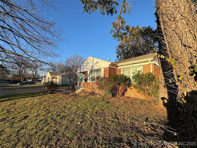 view of property exterior with a yard, brick siding, and crawl space