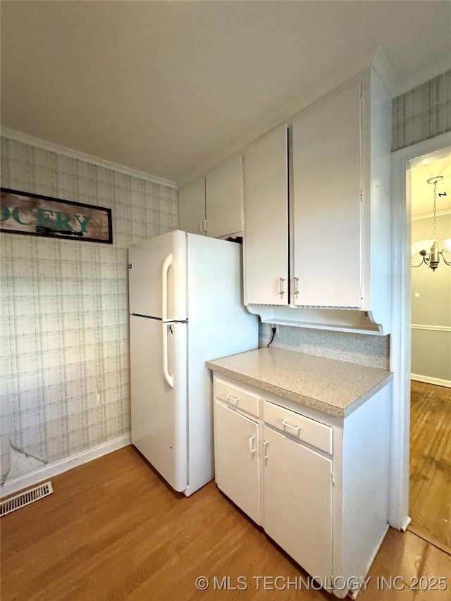 kitchen featuring freestanding refrigerator, wallpapered walls, light wood-style floors, and visible vents