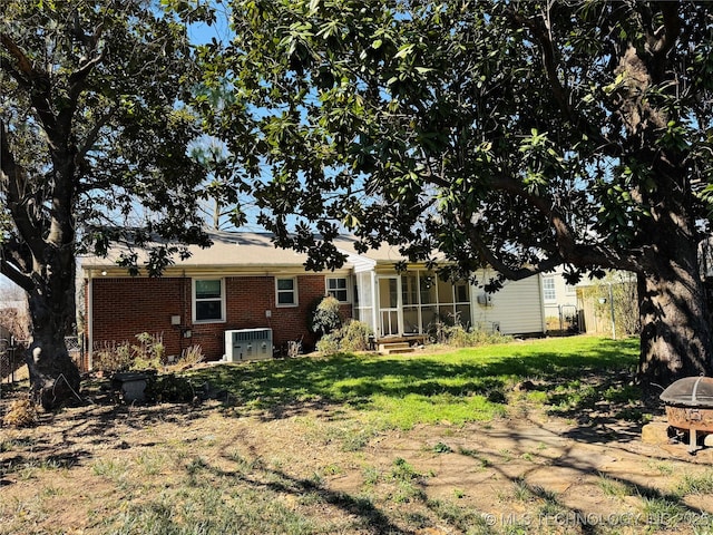 rear view of property featuring brick siding, fence, and a yard