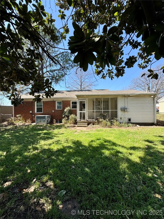 rear view of property featuring brick siding and a yard