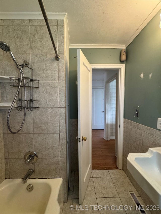 full bath featuring tile walls, visible vents, crown molding, shower / bath combination, and tile patterned flooring