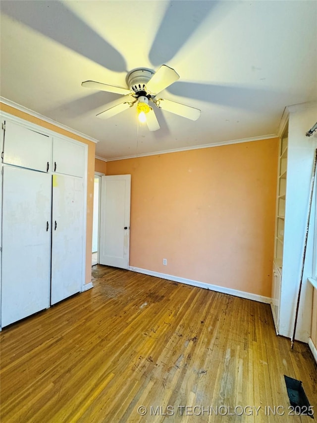 unfurnished bedroom with baseboards, a closet, crown molding, and wood-type flooring