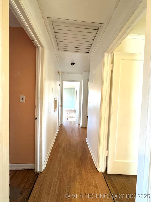 hall with baseboards, crown molding, and wood finished floors