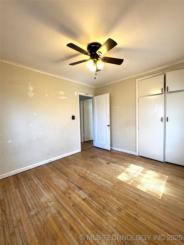 unfurnished bedroom with hardwood / wood-style floors, crown molding, and baseboards