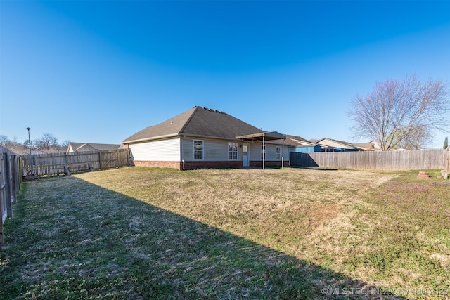 back of property featuring brick siding, a lawn, and a fenced backyard