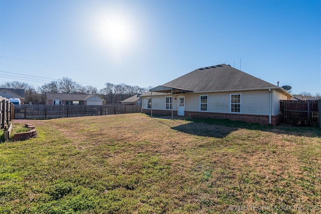 rear view of property featuring a lawn, brick siding, and a fenced backyard