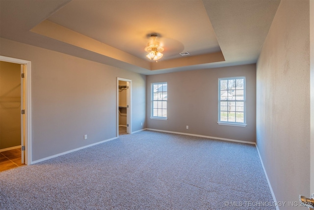 unfurnished bedroom featuring visible vents, baseboards, carpet, and a tray ceiling