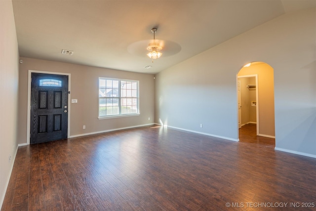 interior space featuring visible vents, a ceiling fan, arched walkways, baseboards, and dark wood-style flooring