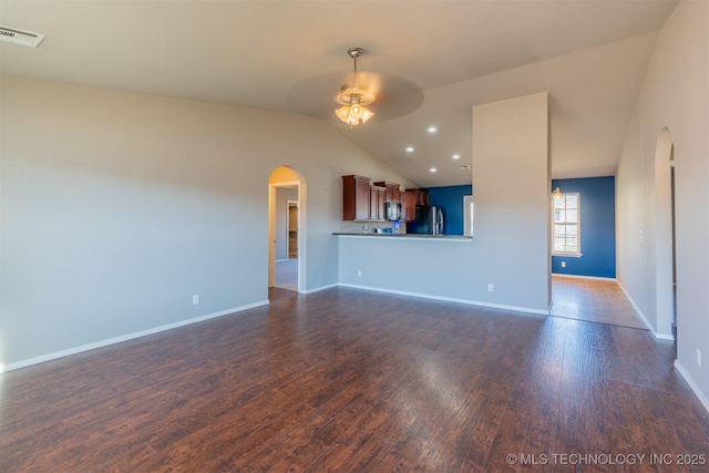 unfurnished living room with visible vents, dark wood-style floors, arched walkways, lofted ceiling, and ceiling fan