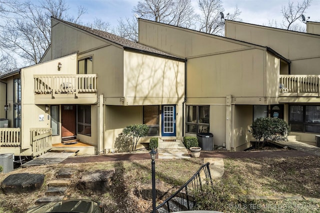 back of house featuring a balcony and a shingled roof