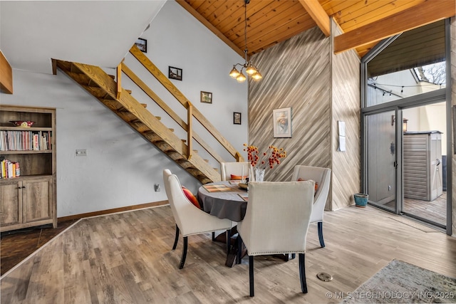 dining area with beamed ceiling, high vaulted ceiling, a notable chandelier, wood finished floors, and stairway