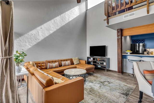 living area with a high ceiling, wood finished floors, and visible vents