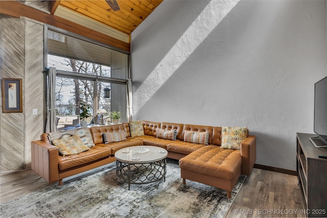 living room featuring wood finished floors, baseboards, wood ceiling, a towering ceiling, and a textured wall