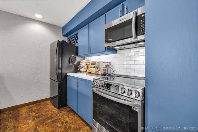 kitchen with blue cabinetry, baseboards, decorative backsplash, appliances with stainless steel finishes, and a textured wall