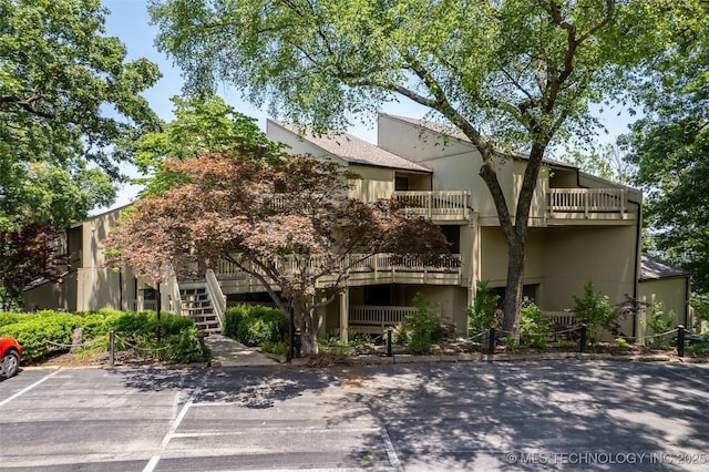 view of building exterior with stairway and uncovered parking