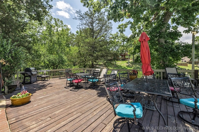 wooden terrace featuring a grill and outdoor dining space