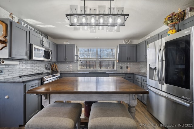 kitchen with gray cabinets, appliances with stainless steel finishes, and wood counters