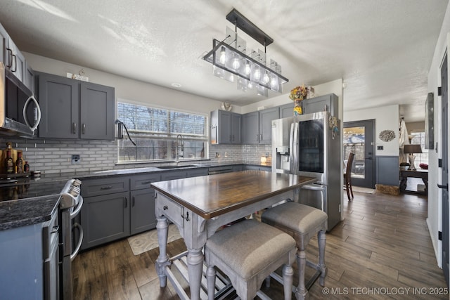 kitchen featuring dark countertops, appliances with stainless steel finishes, gray cabinetry, and a sink