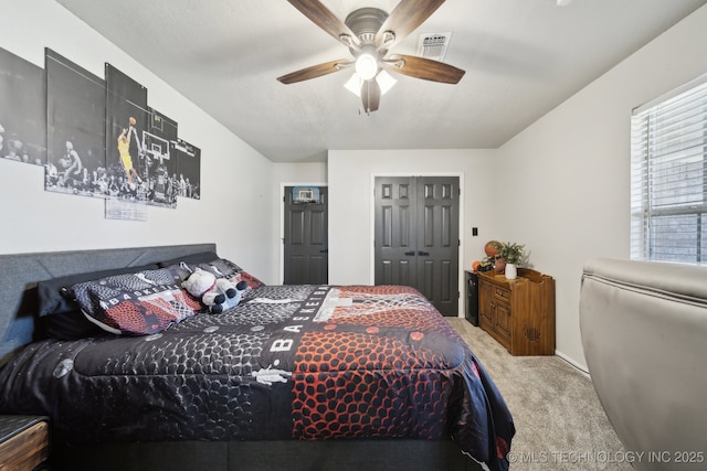 carpeted bedroom featuring visible vents, a closet, and ceiling fan