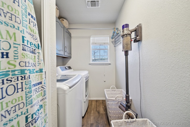 laundry room featuring cabinet space, dark wood-style floors, visible vents, and washing machine and clothes dryer